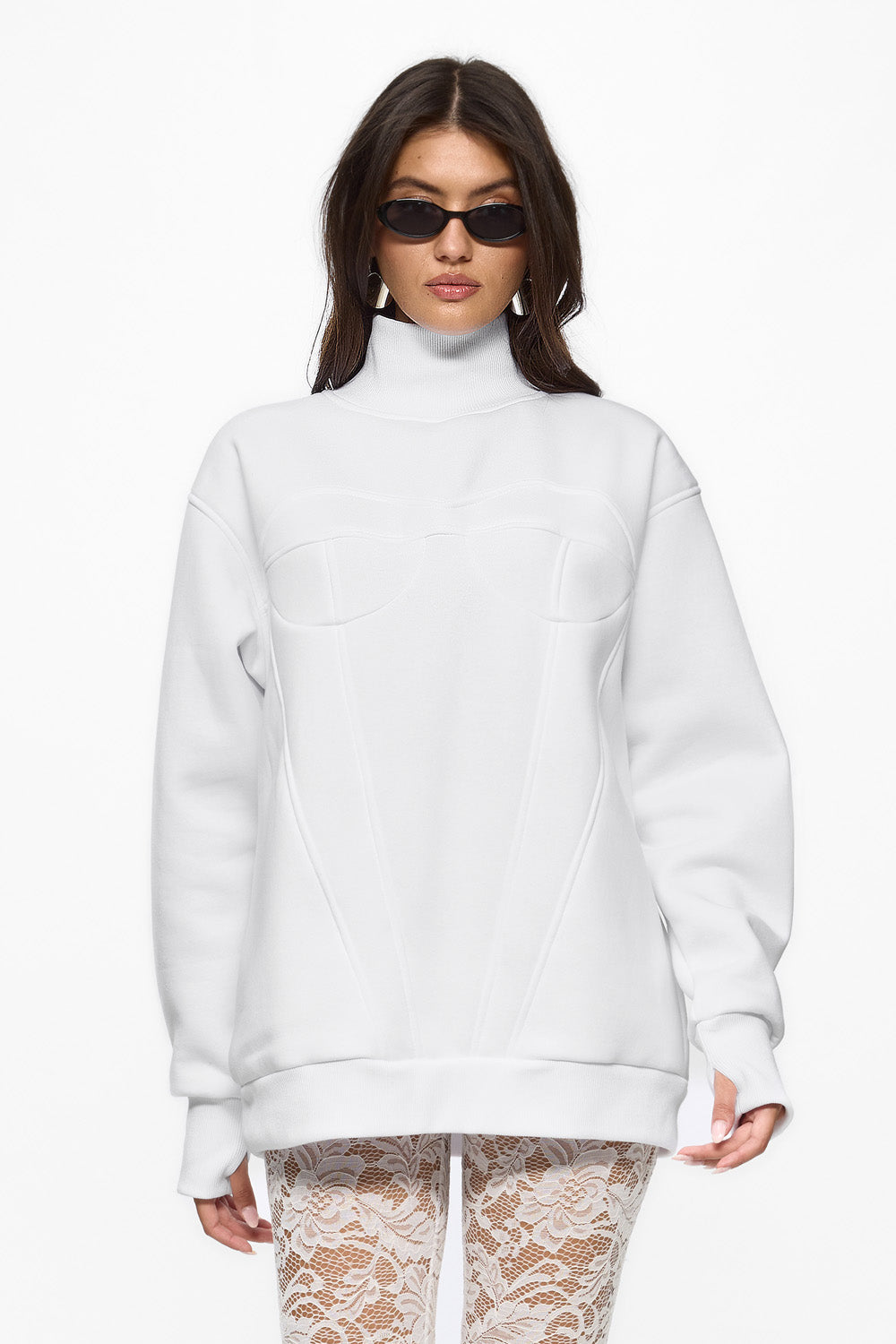 Person wearing a white turtleneck sweater and patterned pants on a white background