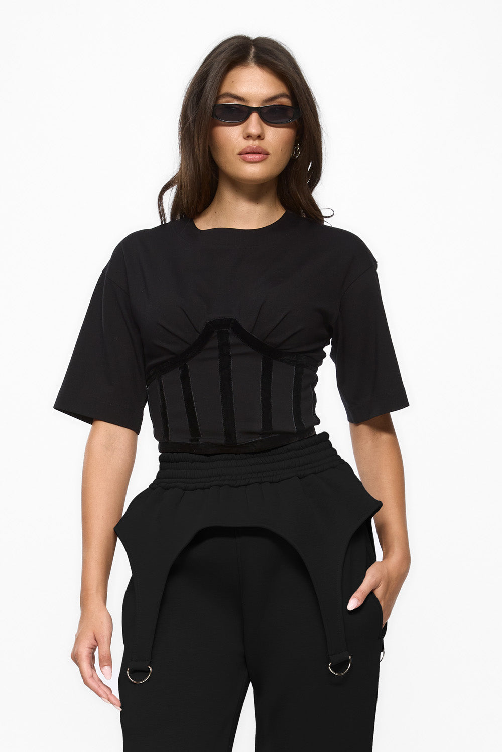 Woman wearing a black outfit with a ruffled top and high-waisted pants on a white background